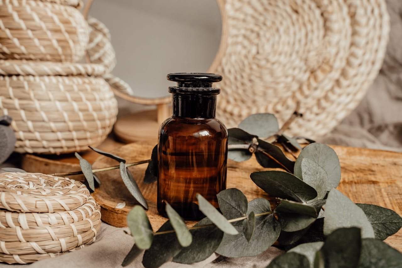 Brown glass skincare bottle amidst natural eucalyptus and woven baskets. Perfect for eco-friendly themes.
